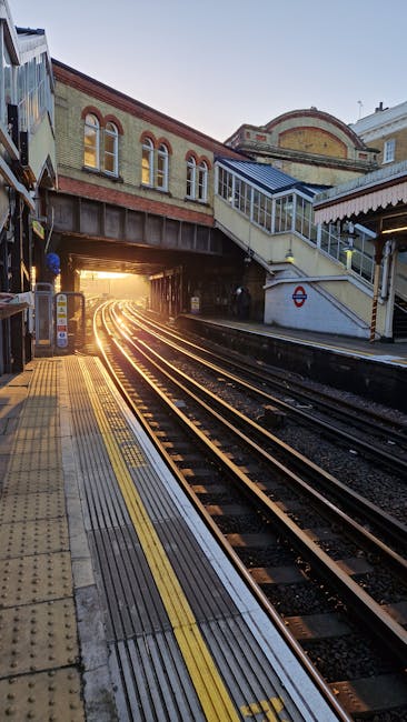 Inside Highbury and Islington station platform during nighttime with dim lighting, showing multiple railway tracks running parallel along the length of the platform. The platform is constructed of con